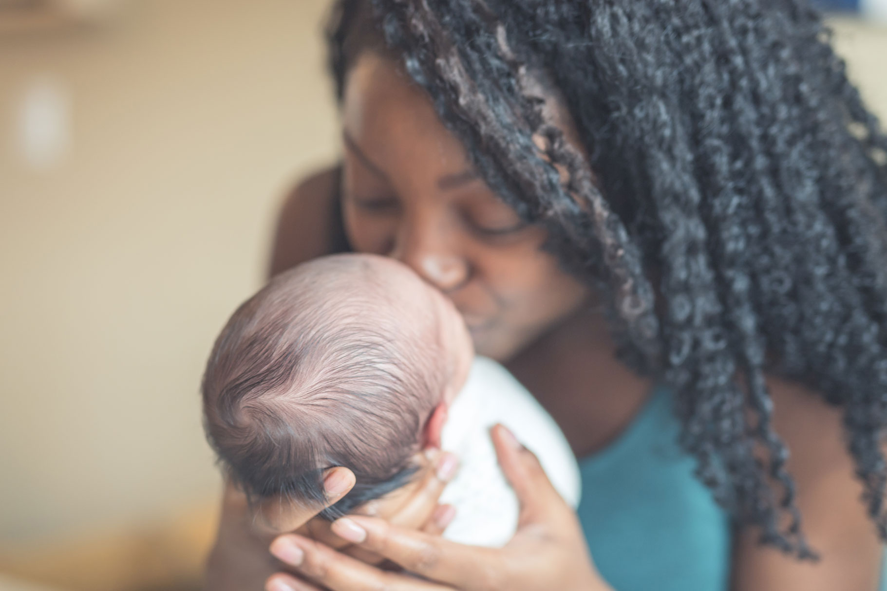 Young mother gently kissing her newborn child