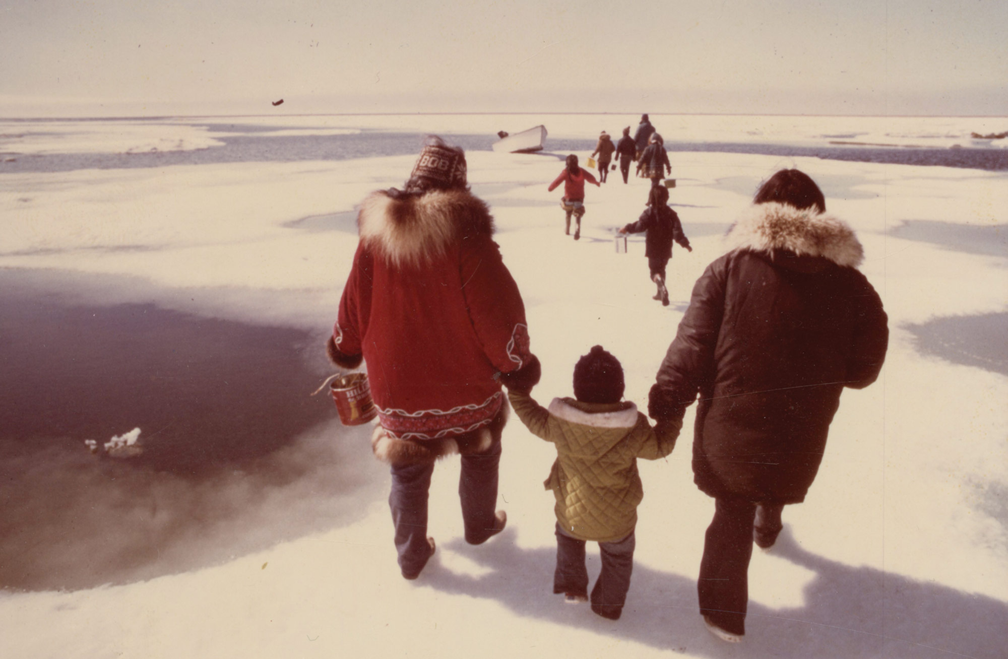 Family walking across snowy landscape in Alaska.