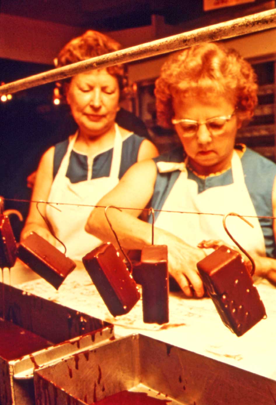 Two chocolate-factory workers inspect desserts