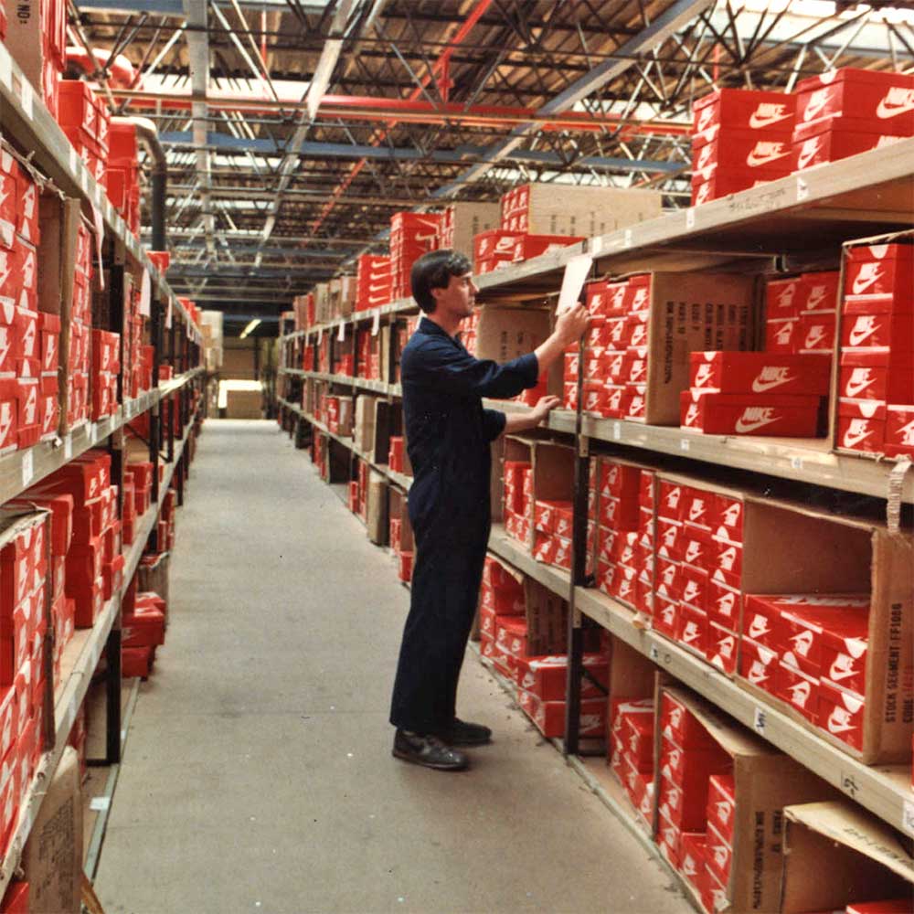 Warehouse worker labors in an aisle full of shoeboxes