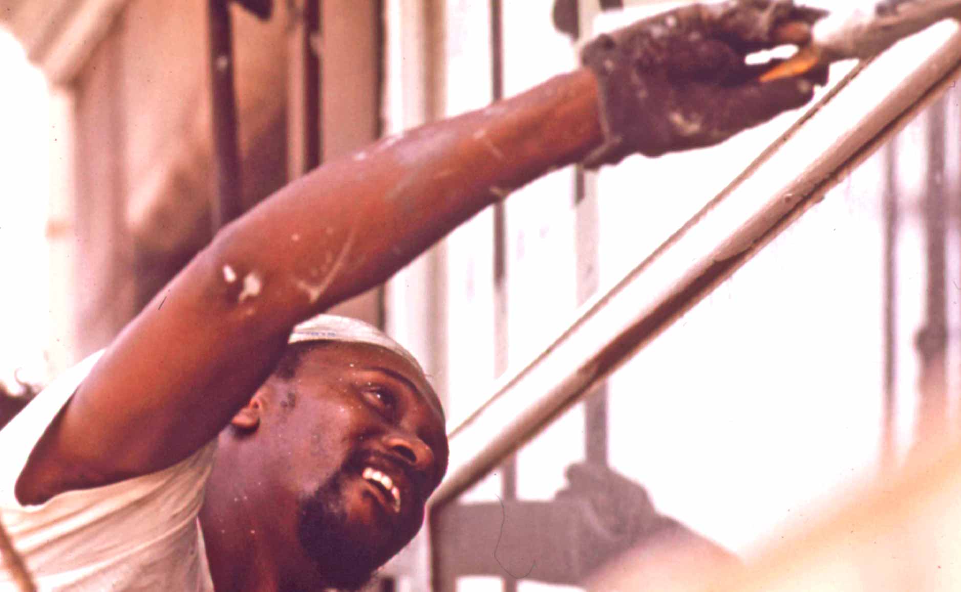 Painter applies a brush to the exterior of a building
