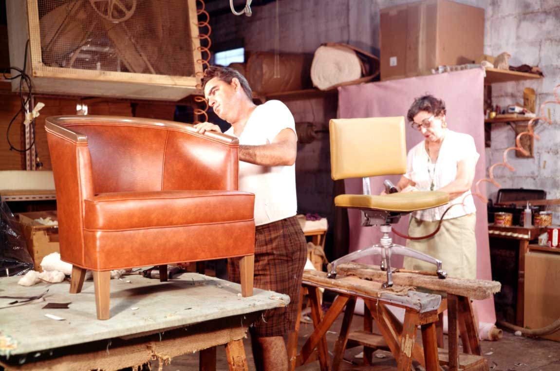 Two workers repairing furniture in an upholstery shop