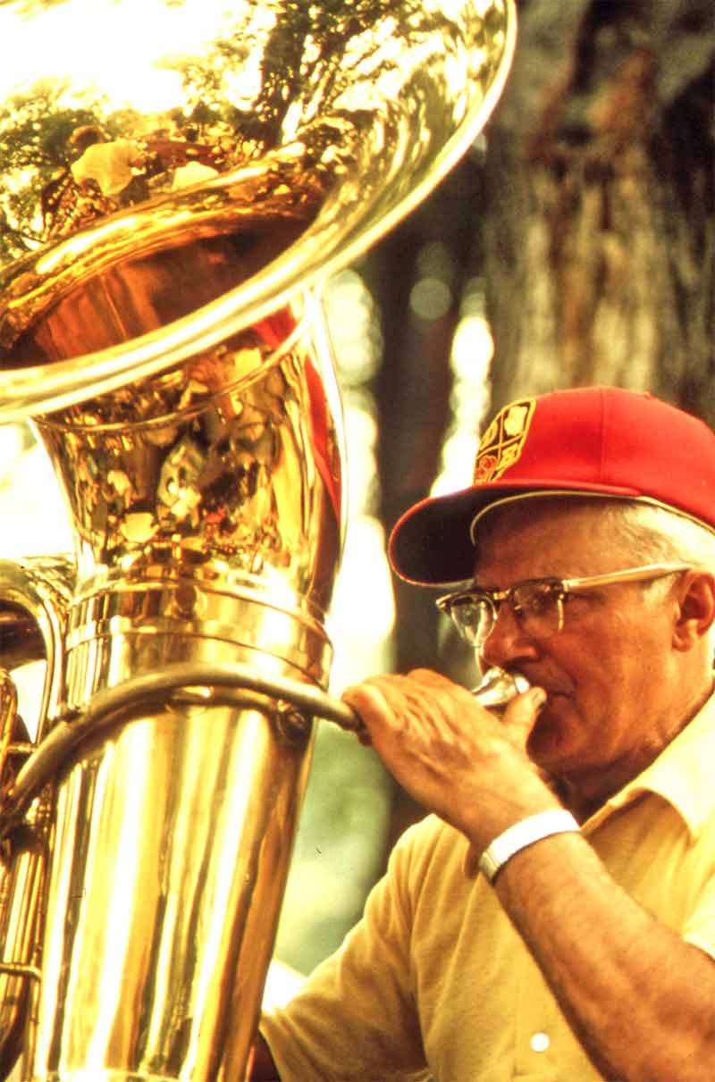 Elderly man plays a tuba outdoors